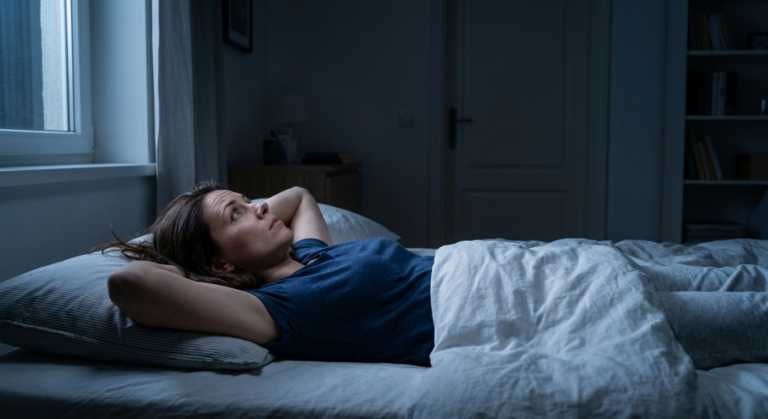 person lying awake in bed at night staring at ceiling unable to sleep naturally